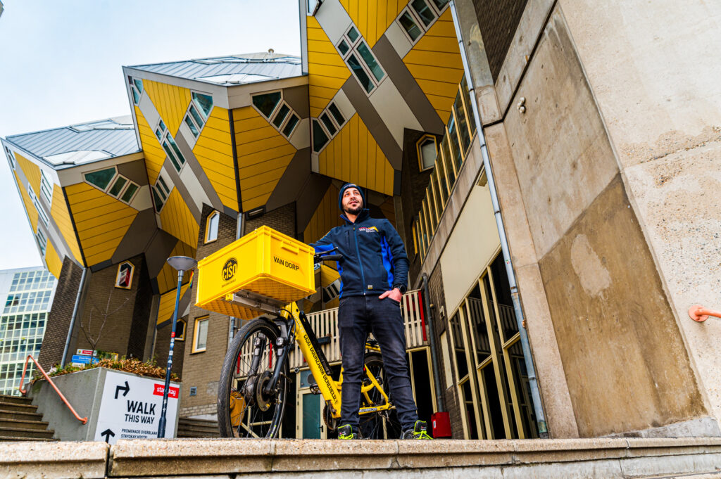 Van Dorp monteur staat met een CISO bakfiets voor de iconische kubuswoningen in Rotterdam