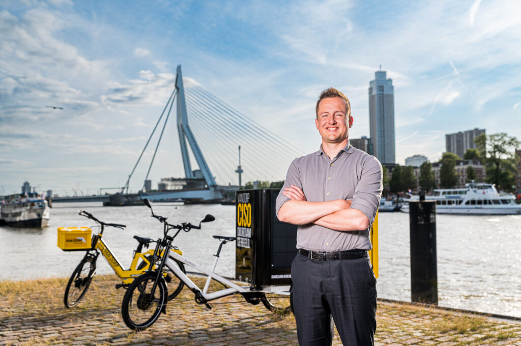 Formulemanager Nick Noordzij poseert met CISO-voertuigen bij de Erasmusbrug in Rotterdam. CISO Rotterdam werd in 2020 gestart.